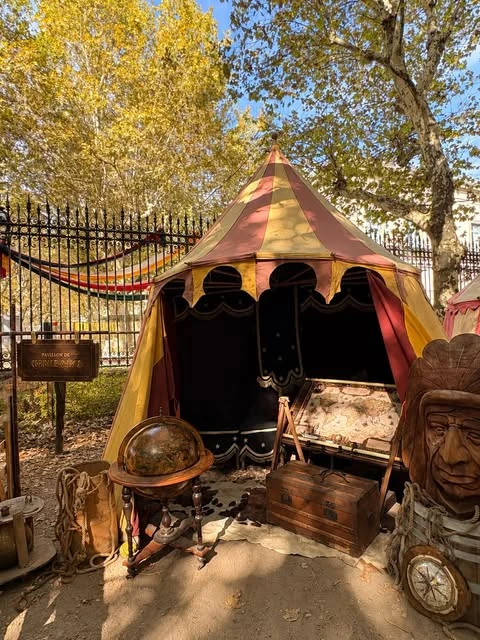Tente rouge et jaune de Lioussac et mobilier du camp sous les arbres