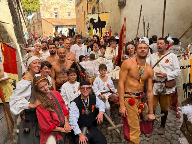 Photo de groupe des membres de Lioussac en costume, dans une rue pavée